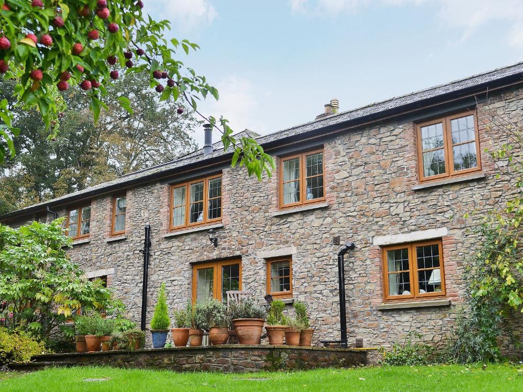 ein Steinhaus mit Topfpflanzen davor in der Unterkunft Grooms Cottage in Westleigh
