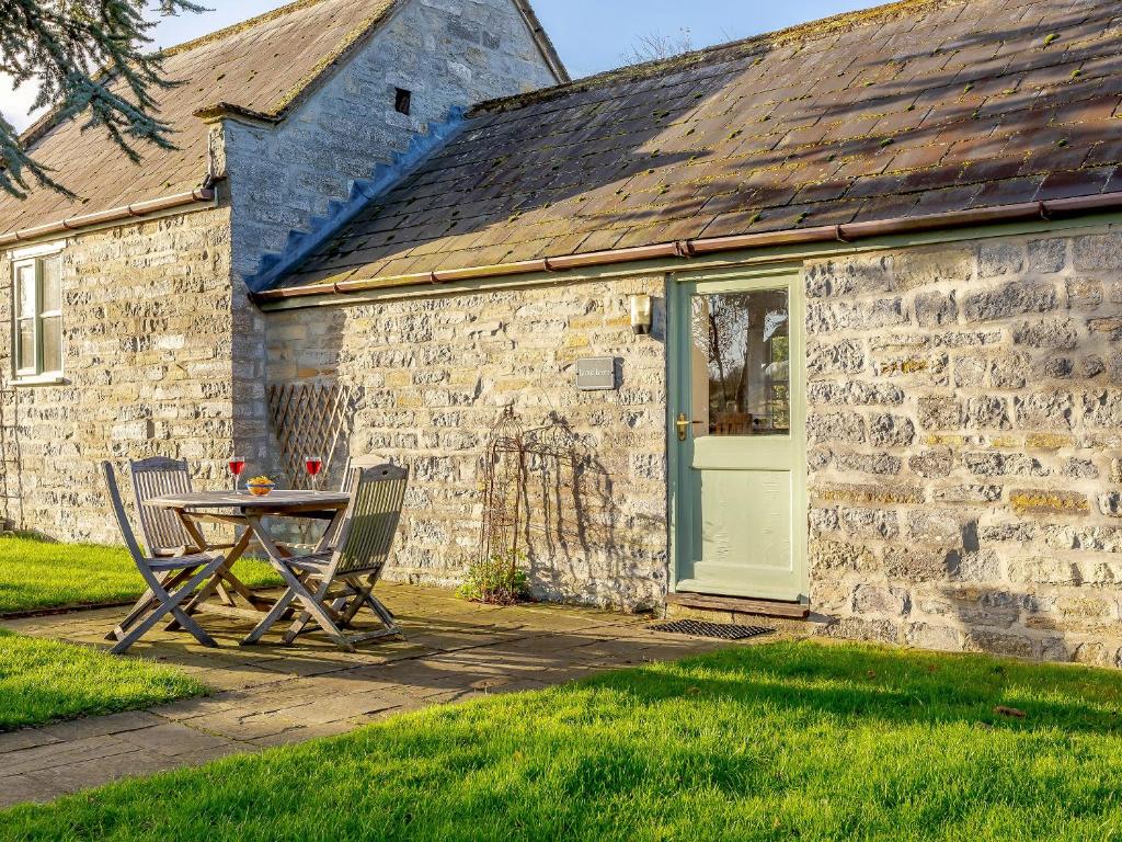 a table and chairs in front of a stone building at Long Barn - Uk30435 in Kingsbury Episcopi