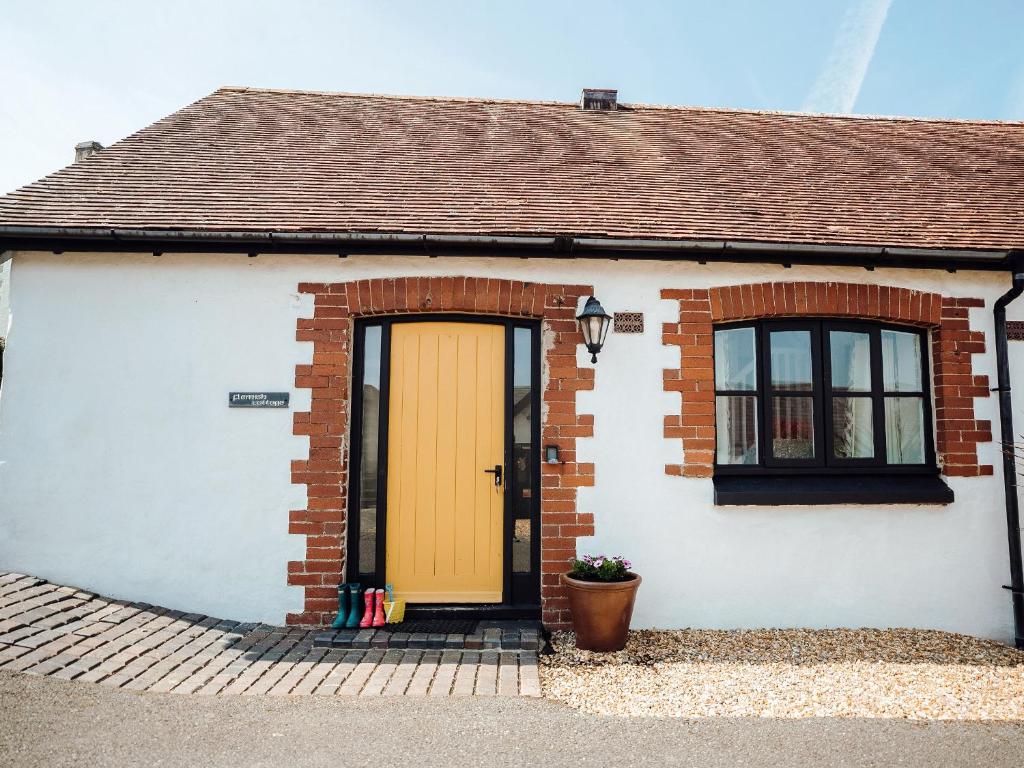 a brick house with a yellow door and windows at Flemish Cottage - Uk6720 in Lydstep