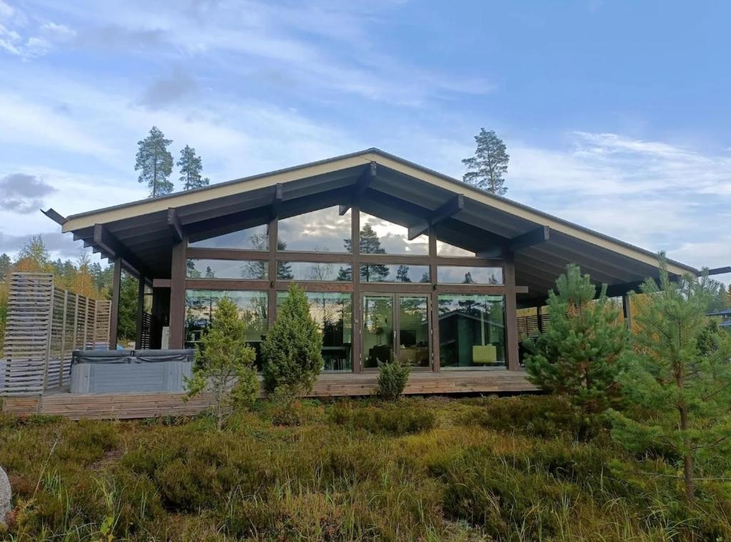 ein Haus mit großen Glasfenstern auf einem Feld in der Unterkunft Naava Resort Luppo - Upea huvila järvinäkymällä in Ähtäri
