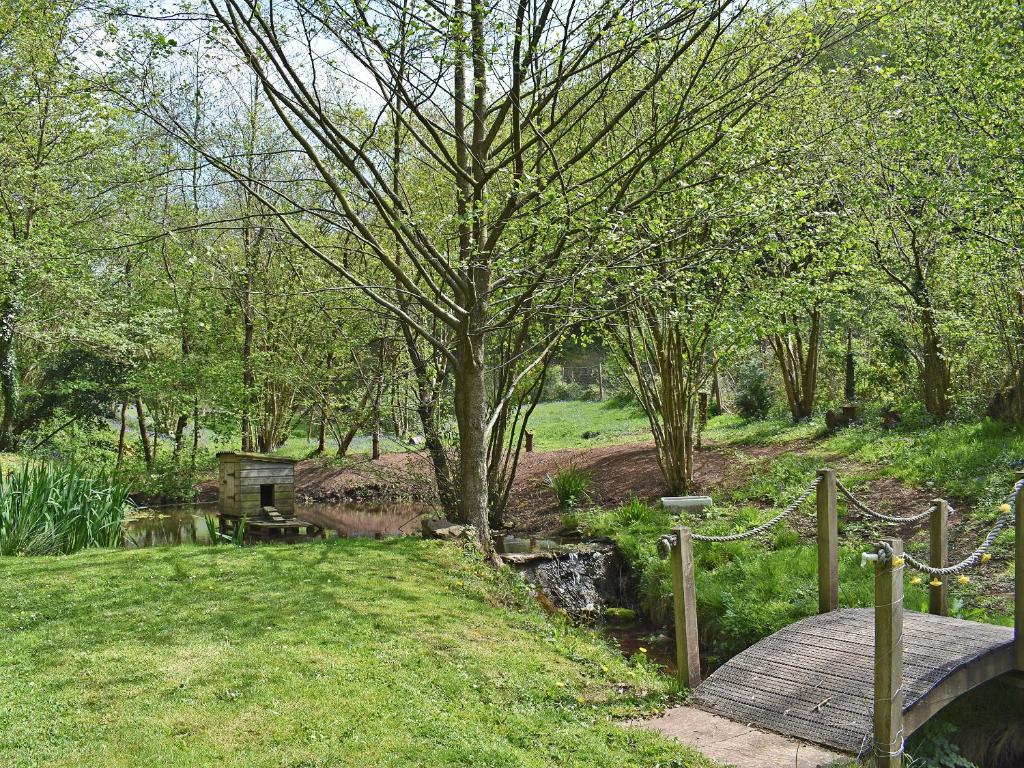 a wooden bridge over a river with a tree at Perivale Lodge in Lydney