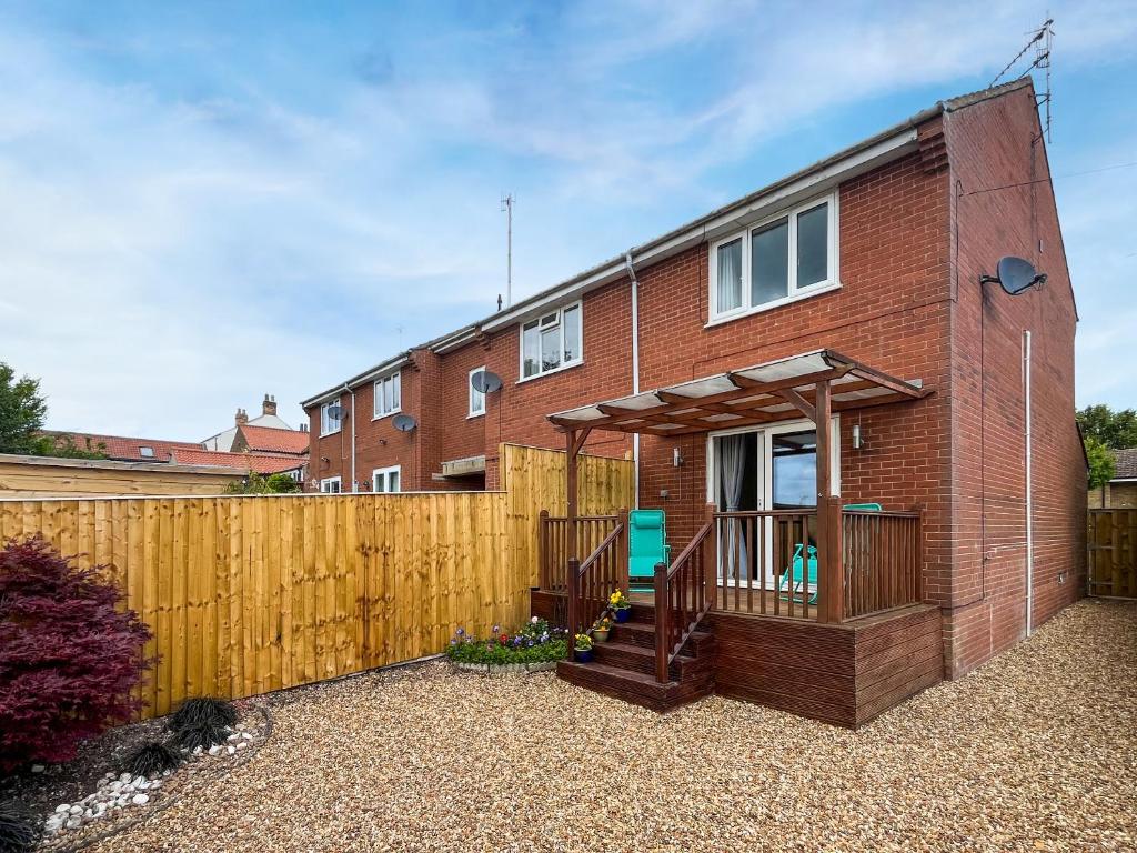 ein Backsteinhaus mit einem Holzzaun davor in der Unterkunft Cayton Cove Cottage in Cayton