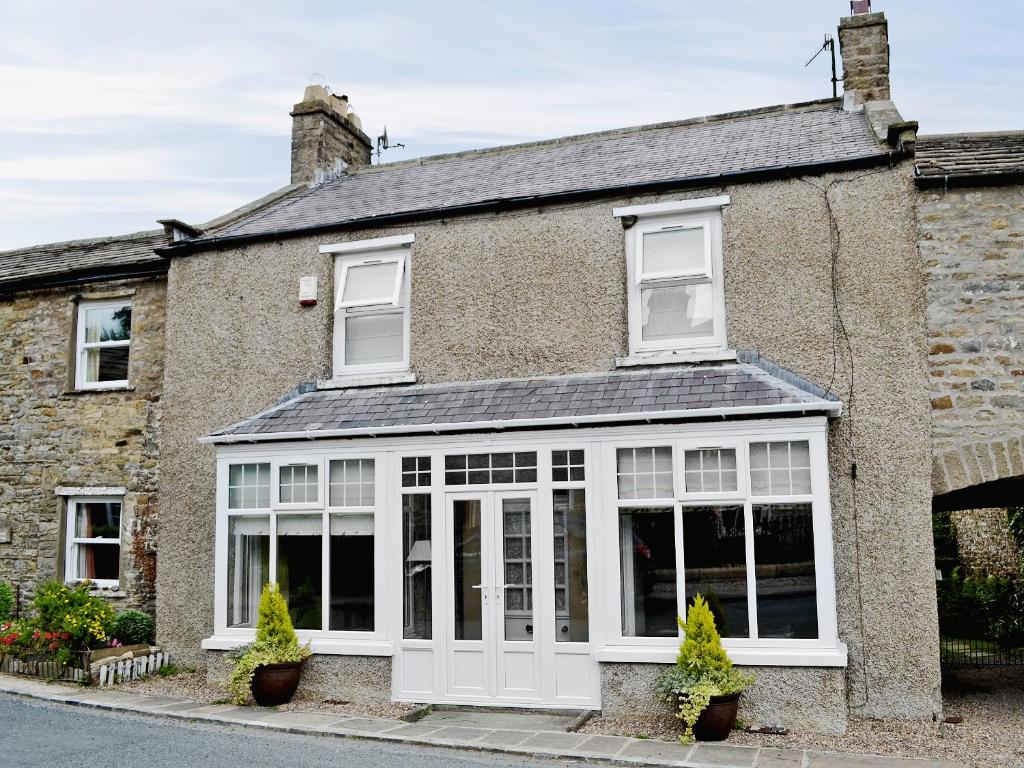 an old brick house with white doors and windows at Craven House in West Burton
