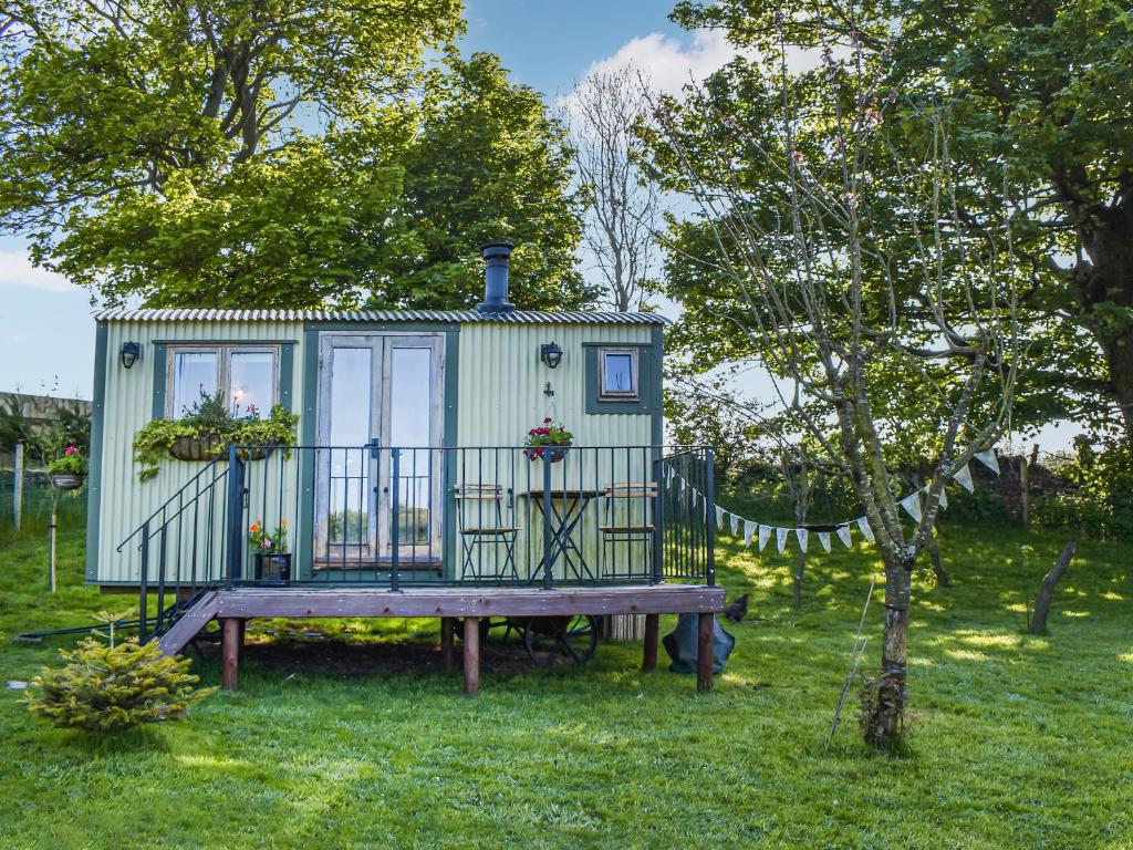 a green tiny house sitting on a wooden table at Shepherds Hut - Ukc6774 in Llanallgo