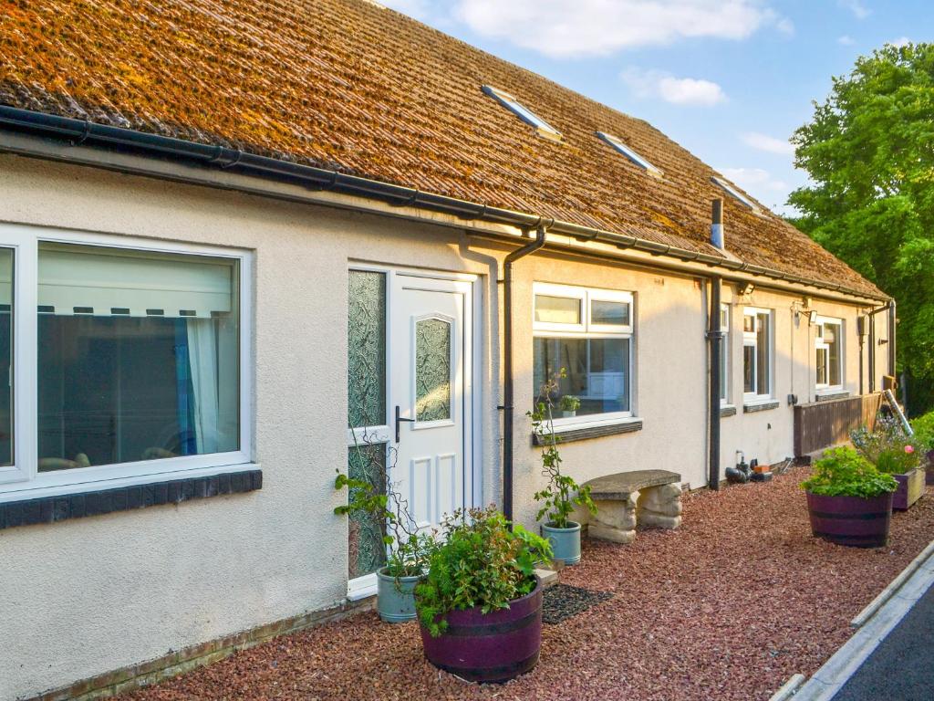 a house with potted plants in front of it at Grooms Cottage in Choppington
