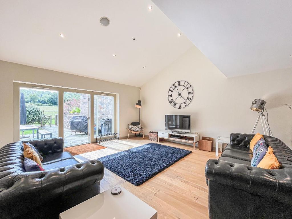a living room with two couches and a clock on the wall at Springfields in North Wootton