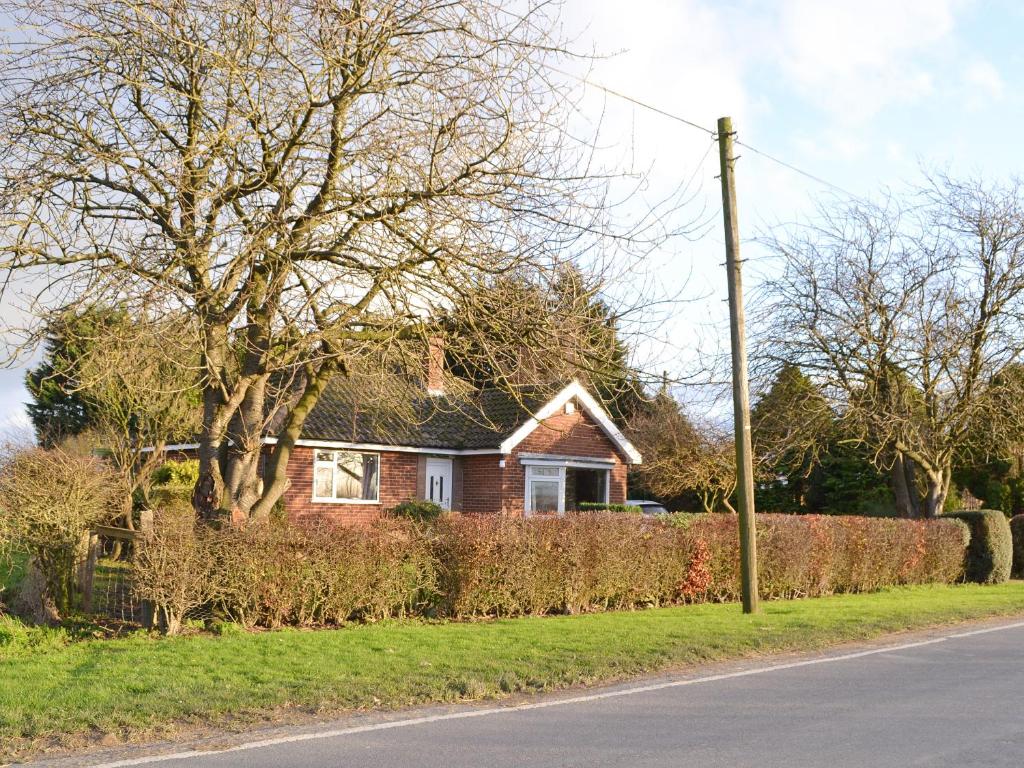 a house on the side of a road with a hedge at Wayside Cottage in Brigham