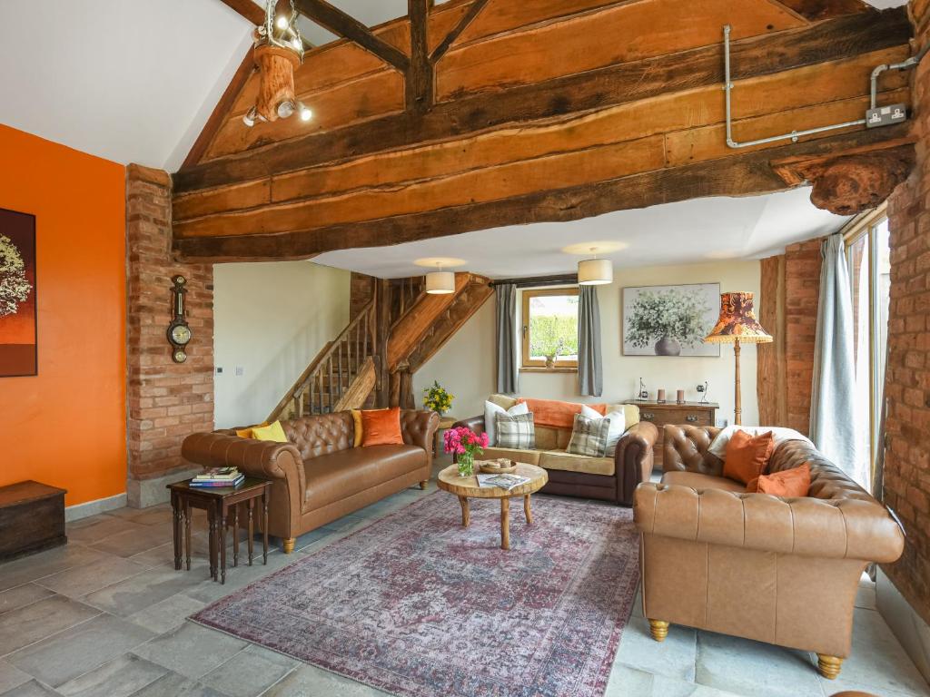 Una sala de estar con muebles de cuero y paredes naranjas. en Orchard Barn - Uk47458, en Chetton