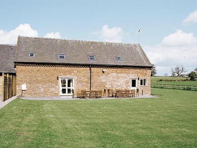 een groot bakstenen gebouw met picknicktafels in een veld bij The Forge in Somersal Herbert