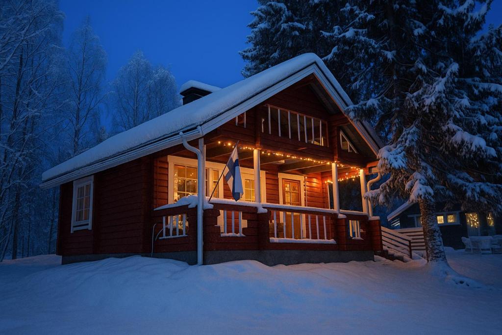 a log cabin in the snow at night at Lapland Aurora Riverside in Raiskio