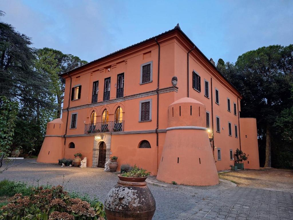 a large orange building with a vase in front of it at Castello Vinci - Dimora di Charme in Vetralla