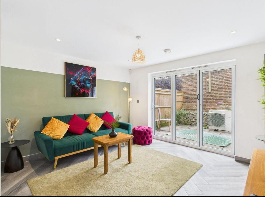 a living room with a green couch with colorful pillows at Elegant 3-Bed Near Station, Pantiles & Calverley in Royal Tunbridge Wells