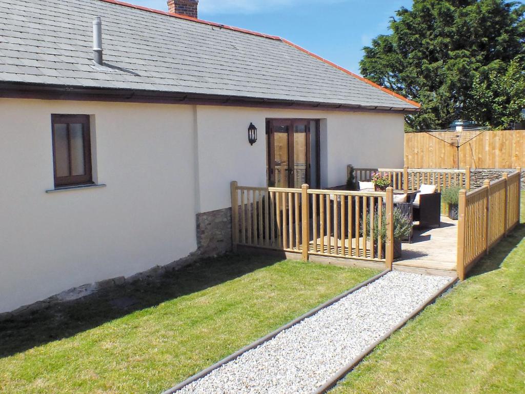 a small white house with a wooden fence at Swallows Retreat in Hartland