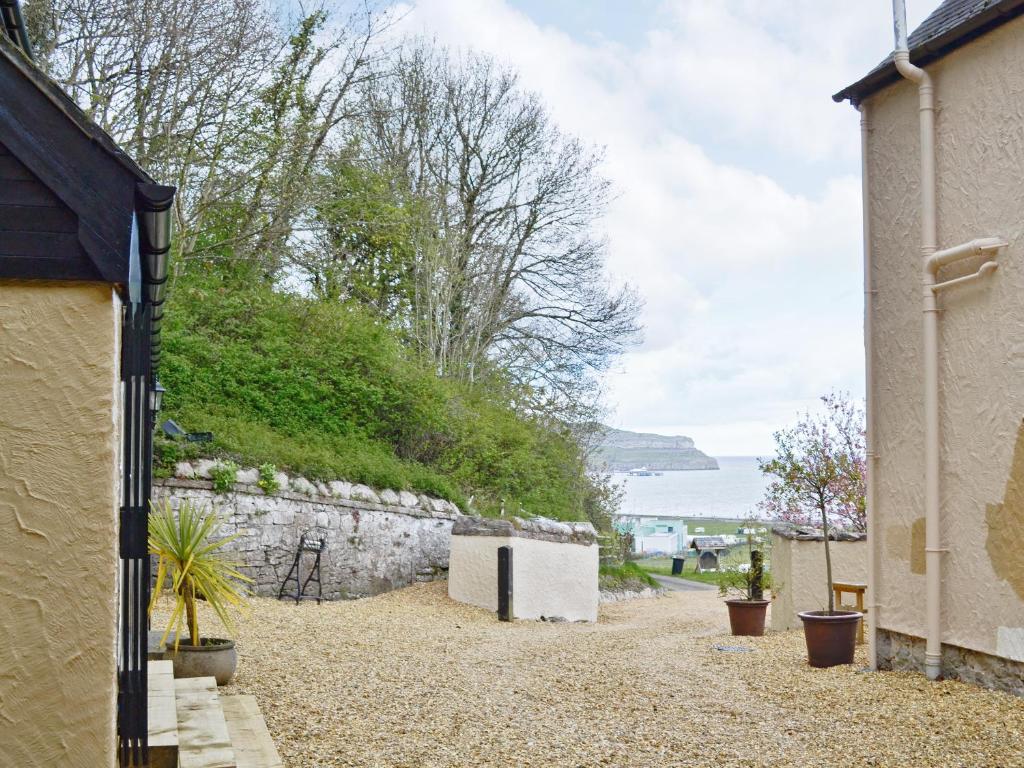 a house with a stone wall next to a street at Scullery Cottage in Penrhyn Bay