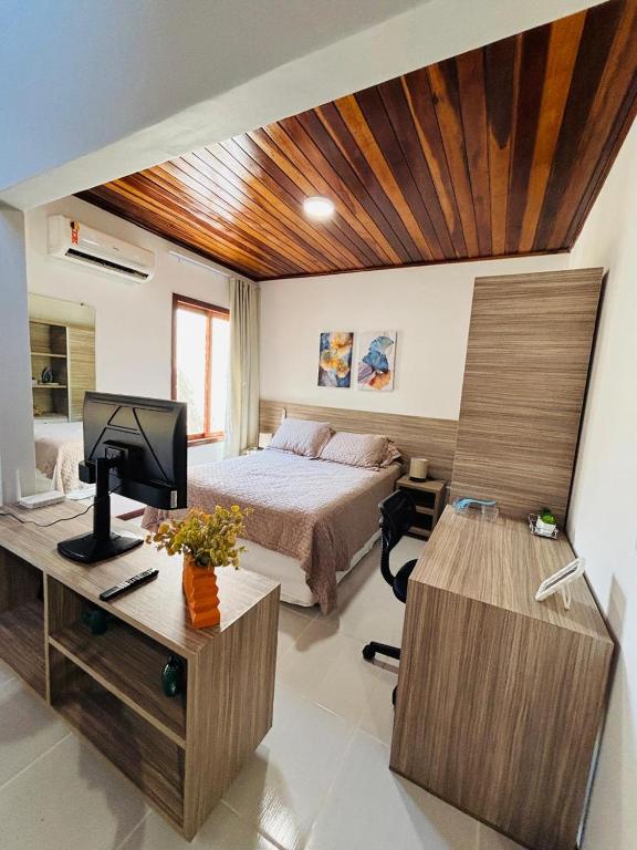 a bedroom with a bed and a desk with a computer at Chale Pitanga 38 in Pipa