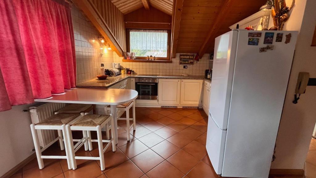 une cuisine avec un réfrigérateur blanc et une table dans l'établissement Lauton Dolomiti Relax Apartment - mit Jacuzzi-Badewanne, à Ziano di Fiemme