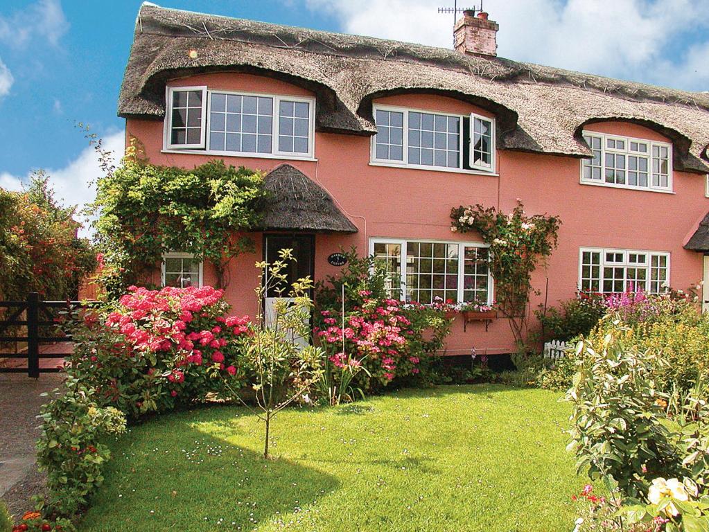 une maison rose avec des fleurs dans la cour dans l'établissement Harbour Cottage, à Winterton-on-Sea