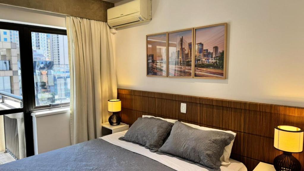 a bedroom with a bed and a large window at Itaim Bibi Flat com varanda in Sao Paulo