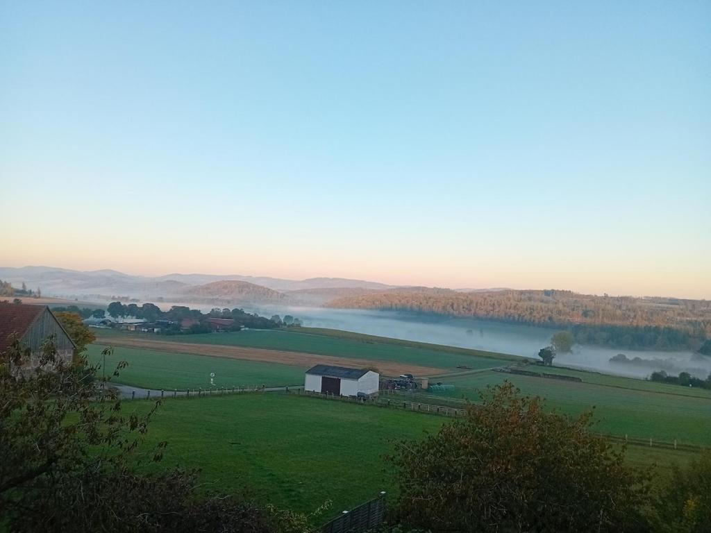 a view of a river with a barn in a field at Casa Lobi - Die Ferienwohnung mit Ausblick! in Korbach