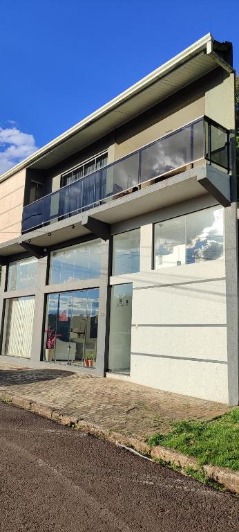 a white building with large windows and a balcony at Doce aconchego in Pato Branco
