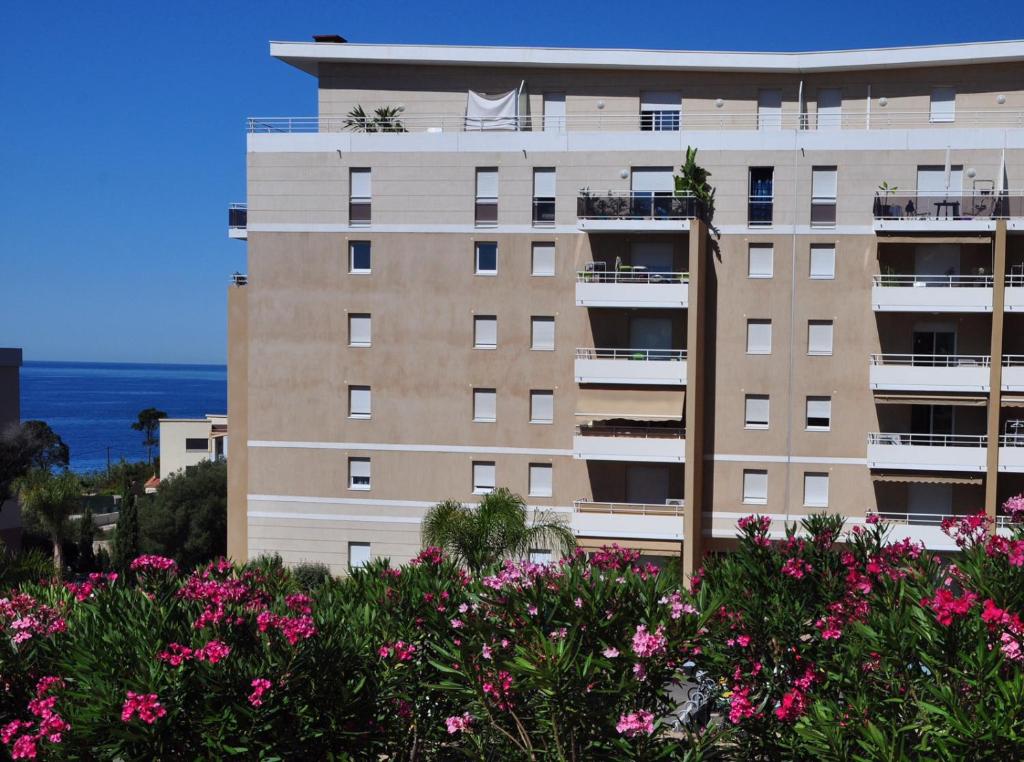 un edificio con flores rosas delante de él en F2 Le Lavezzi en Ajaccio