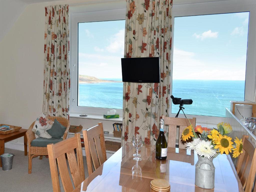 ein Esszimmer mit Tisch und Blick auf das Meer in der Unterkunft Spindrift in Coverack