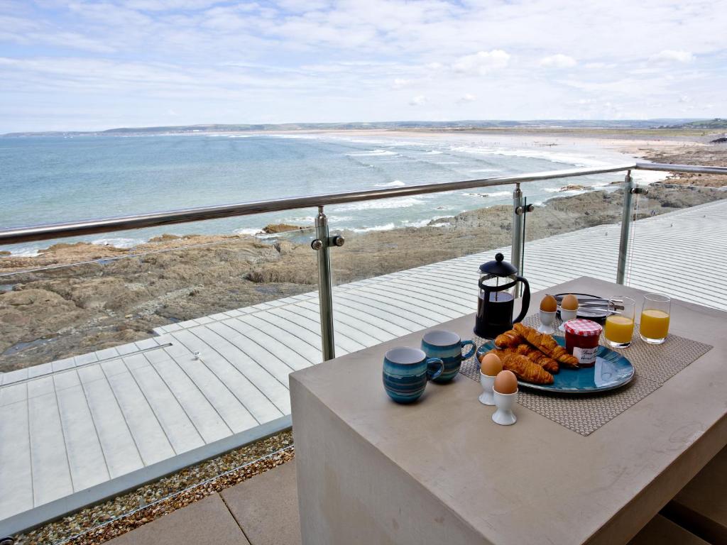 een tafel met een bord eten op een balkon met uitzicht op het strand bij The Penthouse Bay View in Westward Ho