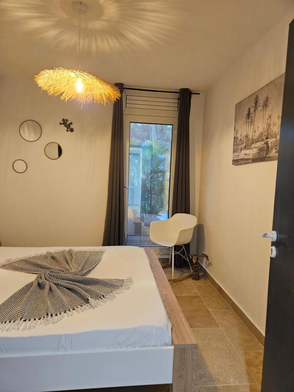 une chambre avec un lit, une chaise et une fenêtre dans l'établissement Antilo - appartement proche mer, au Diamant