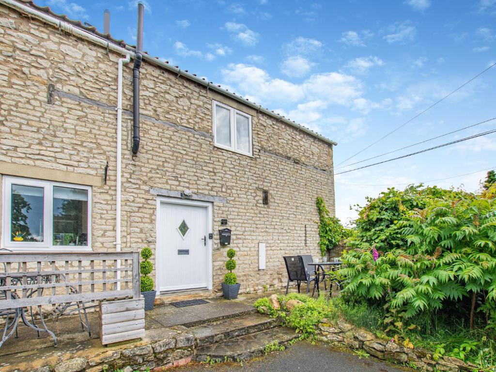 a brick house with a white door and a patio at Church View Cottage - Uk45697 in Pickering