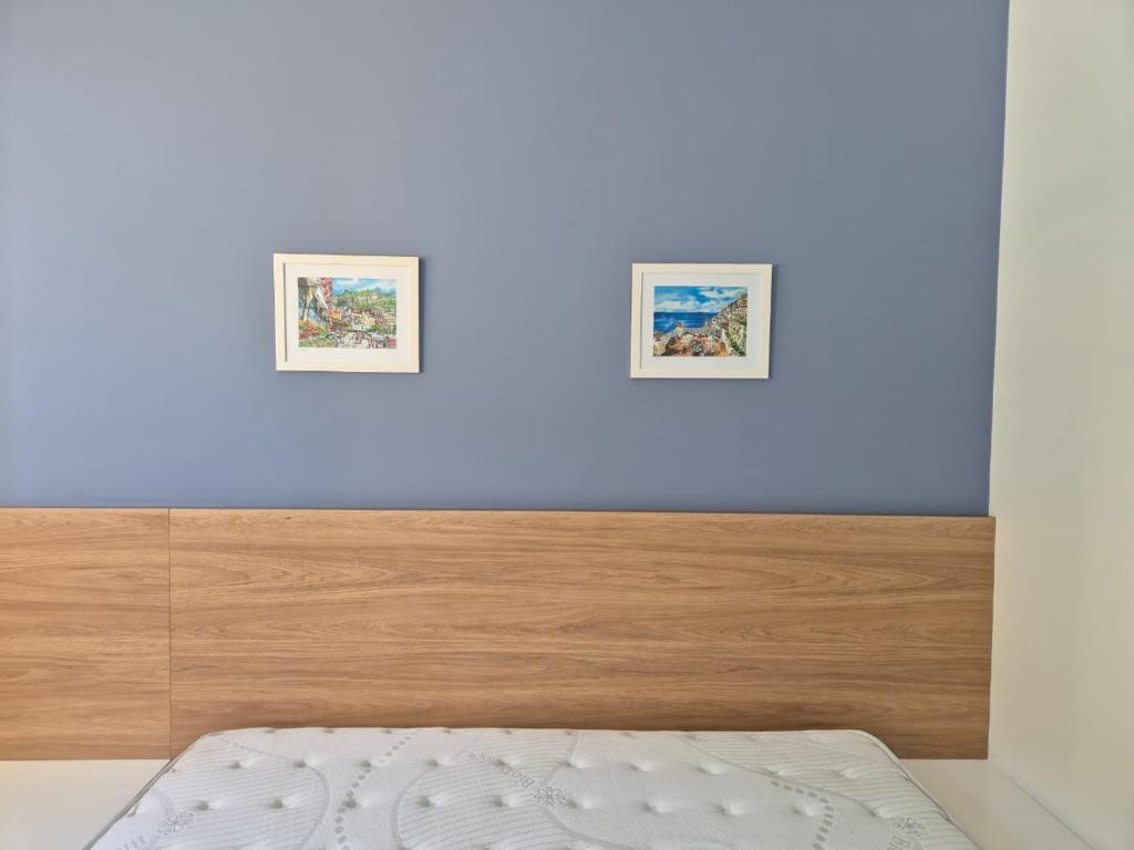 ein Schlafzimmer mit einem Bett und zwei Bildern an der Wand in der Unterkunft Villa sol e mar, seu refúgio em Muro Alto in Ipojuca