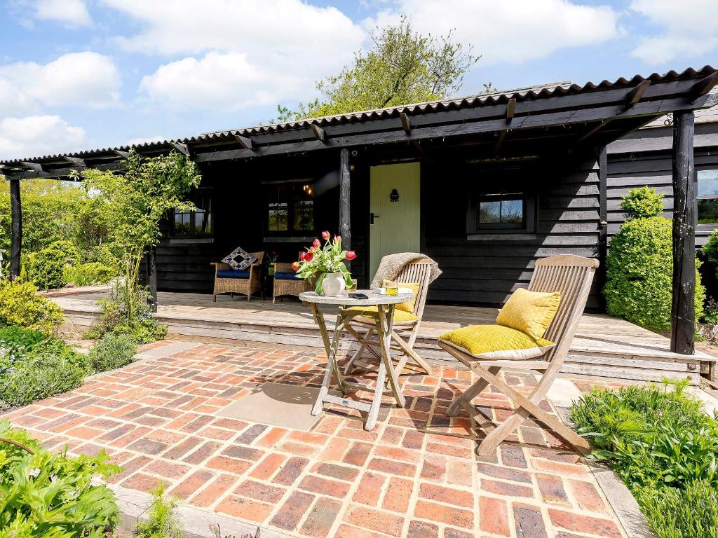 een terras met een tafel en stoelen en een huis bij Brook Farm Annex in Tenterden