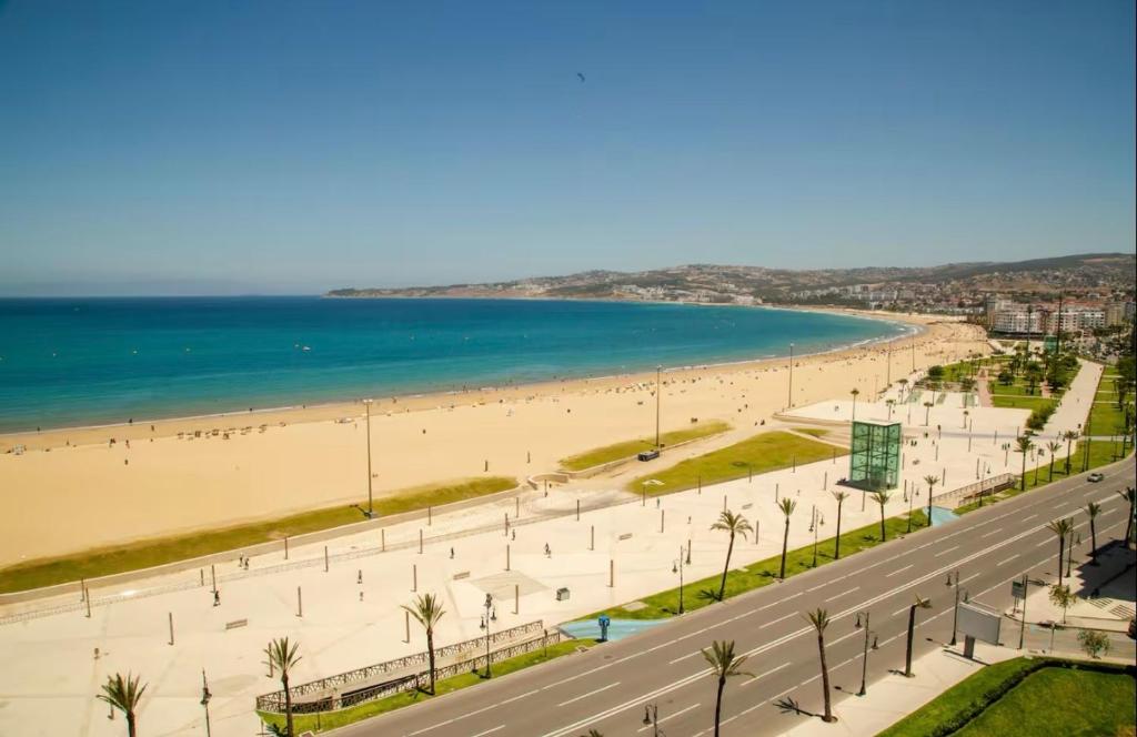 a road next to a beach with palm trees and the ocean at Tradicional & Luxury Apartment City Center & Beach & WiFi! in Tangier