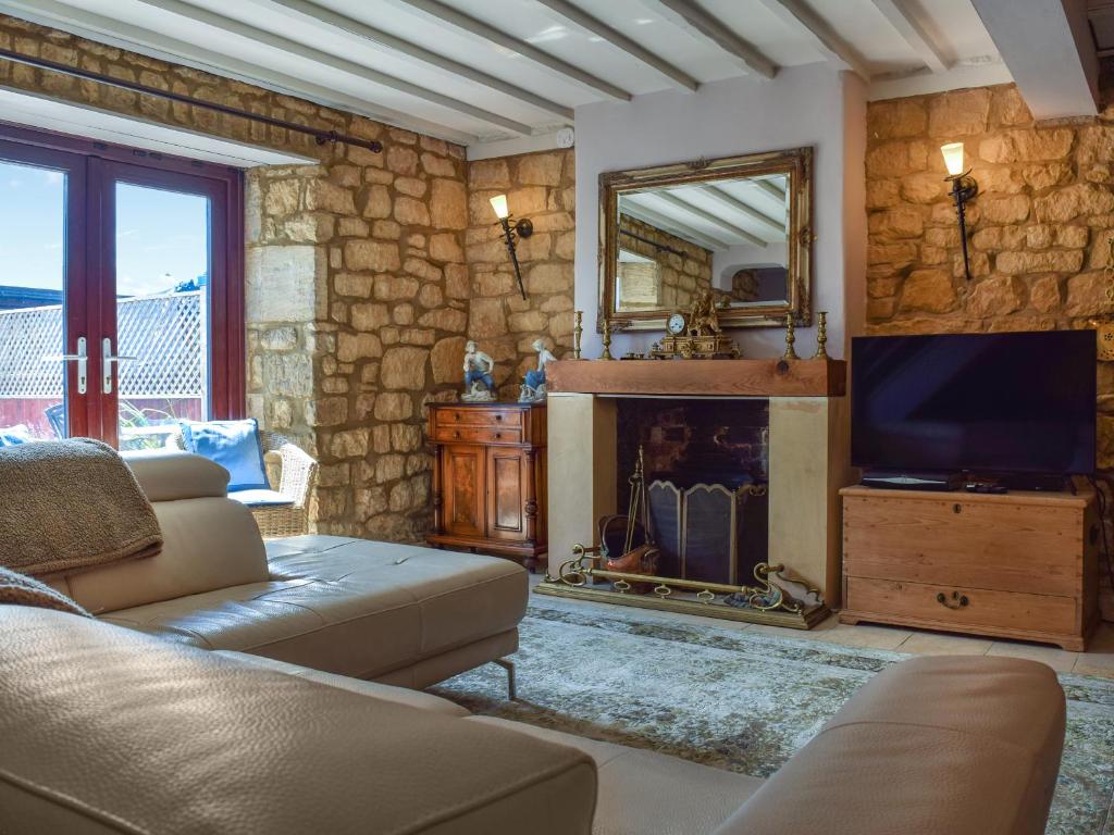 ein Wohnzimmer mit Kamin und Fernseher in der Unterkunft Bow Cottage in Bourton on the Water