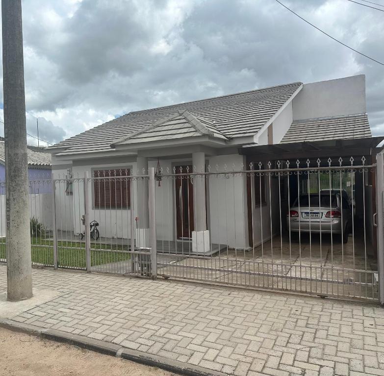 ein weißes Haus mit einem Zaun davor in der Unterkunft Casa Kipper in São Gabriel