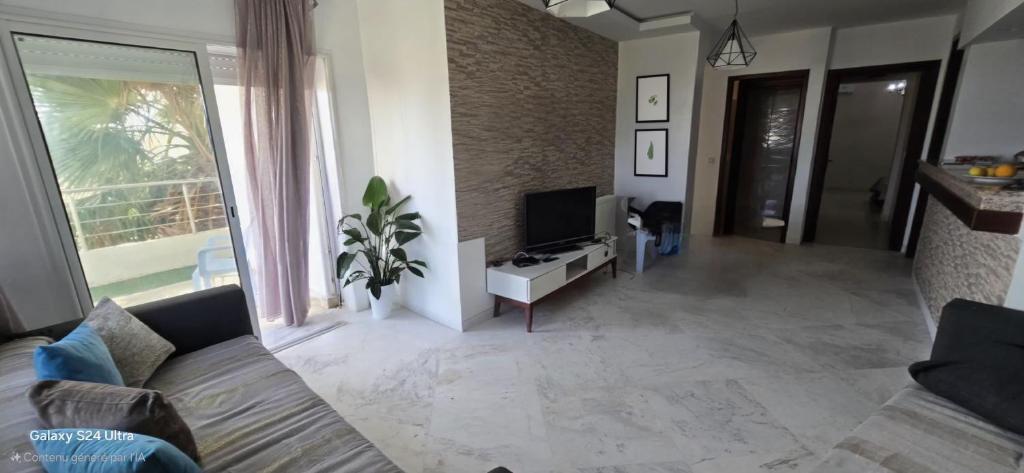 Una sala de estar con un sofá y un televisor. en Résidence soltana Bizerte Vue sur mer, en Dar el Koudia