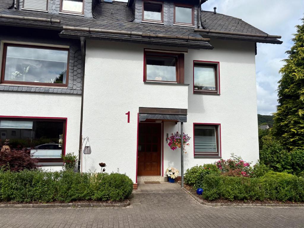 a white house with a red and white door at FeWo Linneweber in Willingen