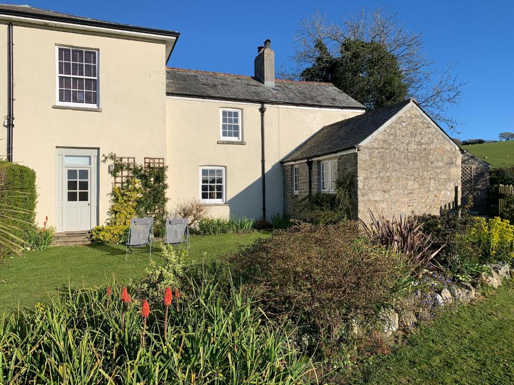 a white house with two chairs in the yard at Gewans Farm Cottage in St Austell