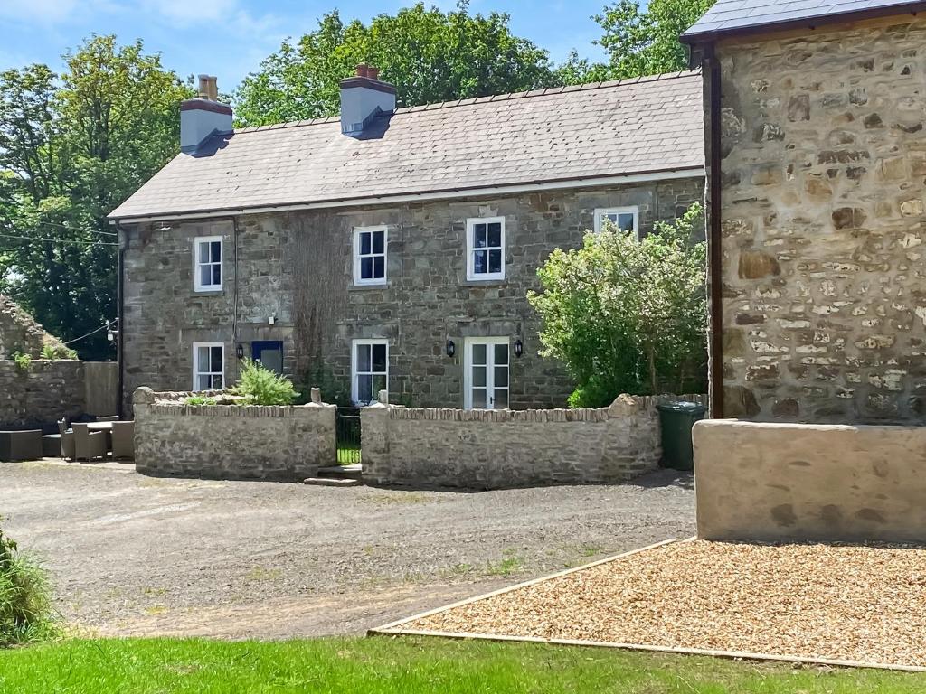 ein altes Steinhaus mit einer Steinmauer in der Unterkunft The Farmhouse in Pelcomb