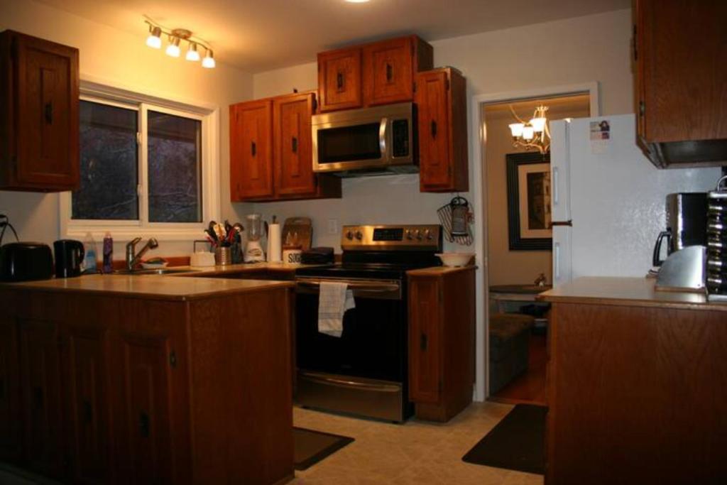 a kitchen with wooden cabinets and a stove top oven at Bungalow in Green Area in Ottawa