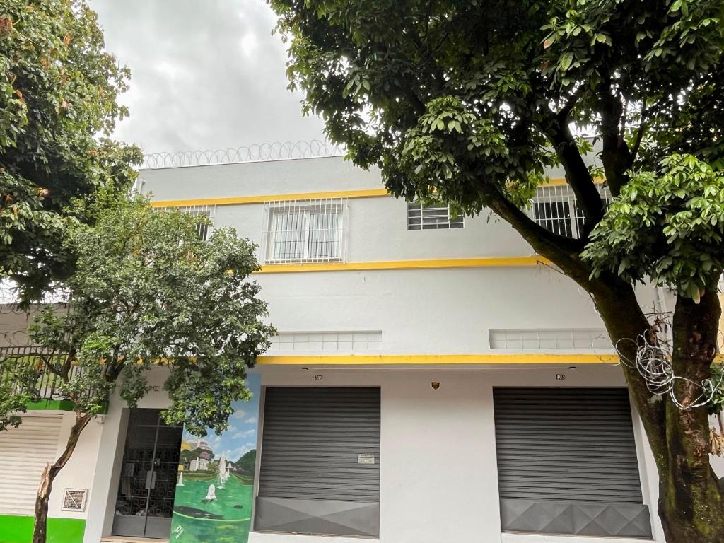 a white building with two garage doors and trees at 4 quartos Conforto e silêncio no coração de BH in Belo Horizonte