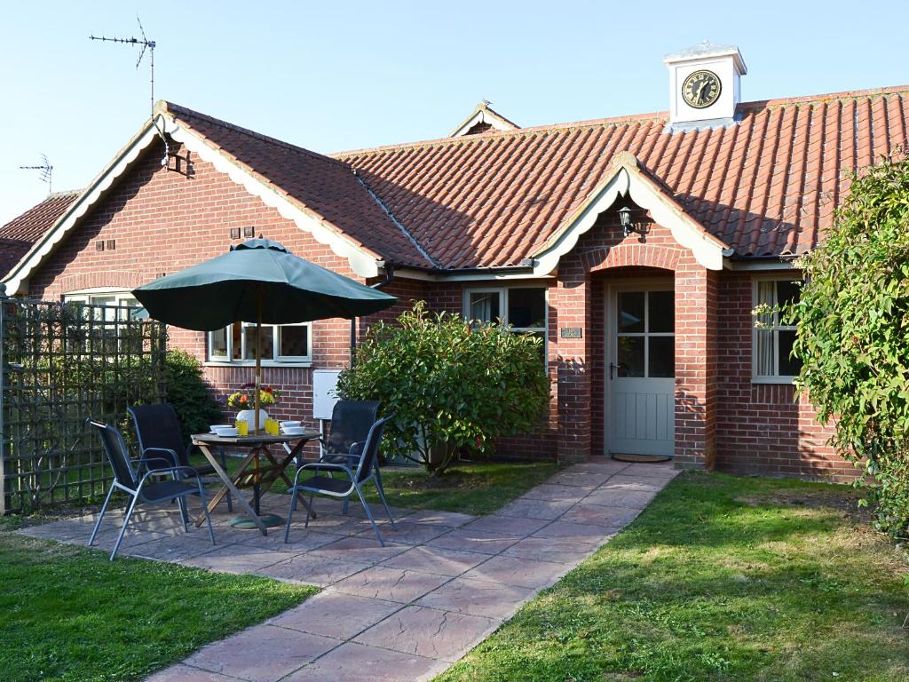 a brick house with a table and an umbrella at Lily Broad Cottage in Burgh Saint Margaret