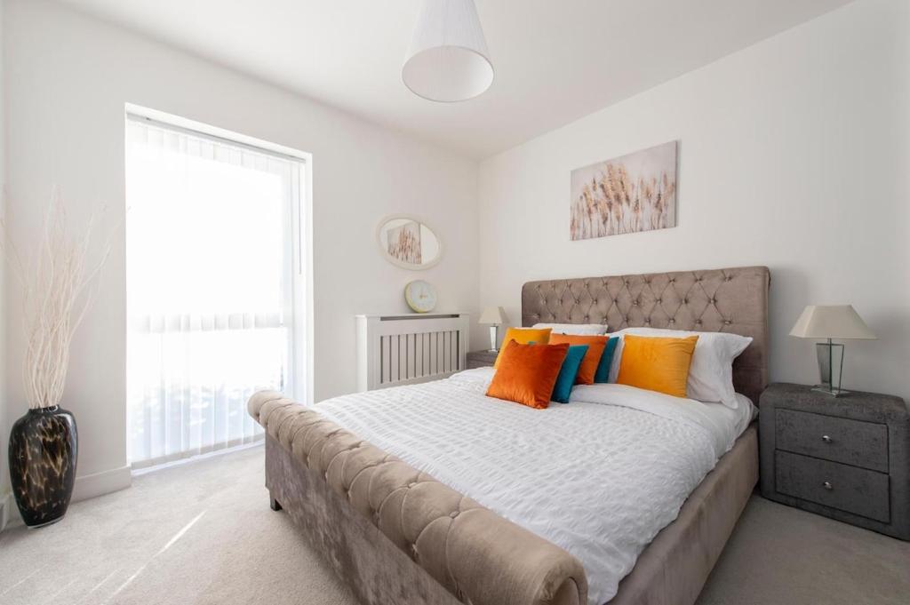 een slaapkamer met een groot bed met oranje en blauwe kussens bij Casa Di Dolce Two Bedroom Apartment with Balcony in Maidstone