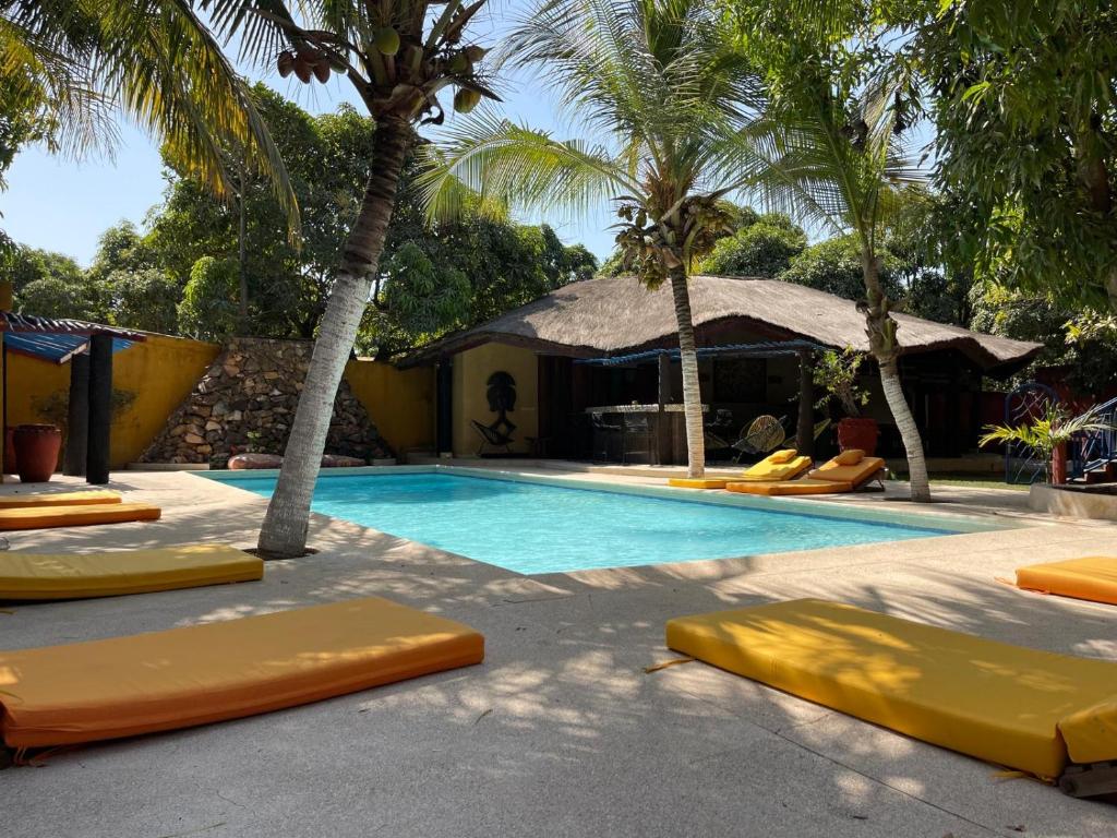 einen Pool mit gelben Liegestühlen und Palmen in der Unterkunft La Tour Rouge in M'bour