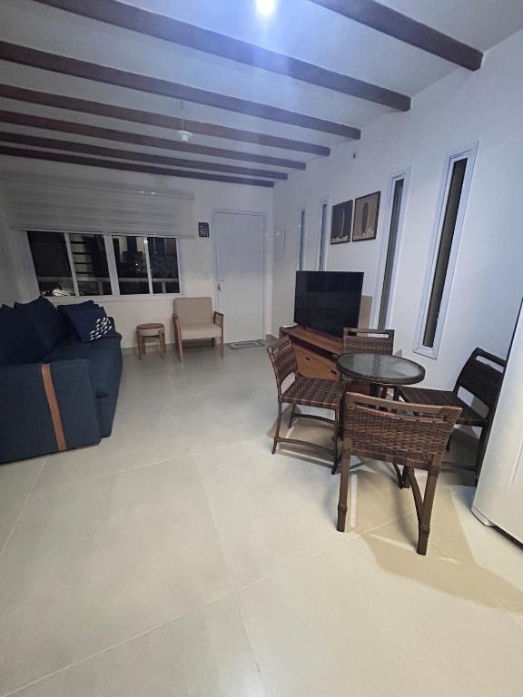 Apartamento Charmoso com Mezanino em Juquehy في ساو سيباستياو: غرفة معيشة مع أريكة وطاولة وكراسي