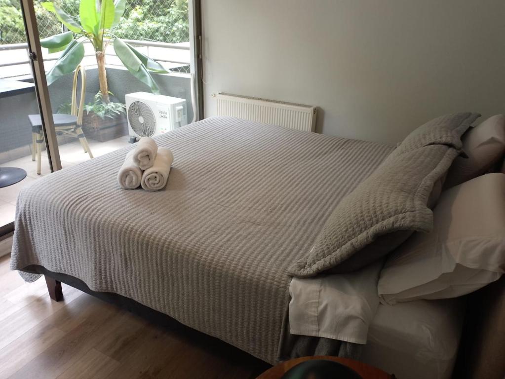 Dos toallas en una cama en un dormitorio con ventana. en Exclusivo depto con AC y piscina Ñuñoa, en Santiago