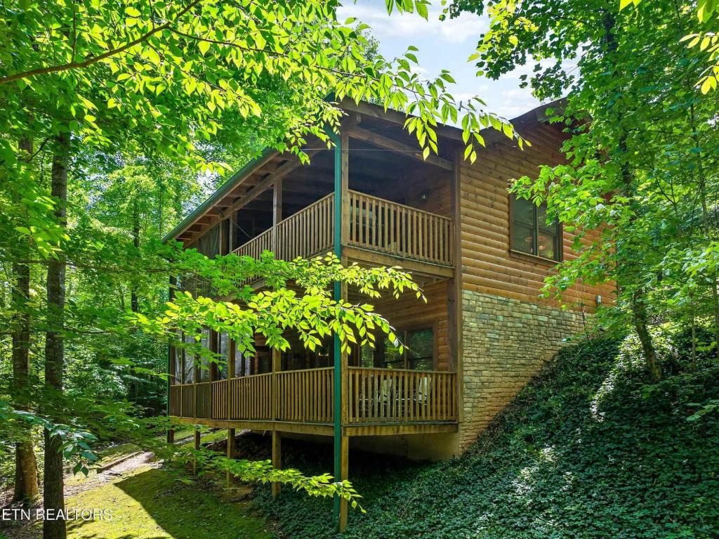 a wooden house with a balcony in the woods at Along the Trail Cabin with Hot Tub Pool Pond Game Room in Wear Valley