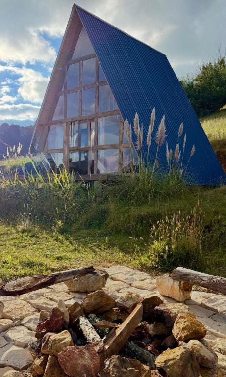 a small house with a blue roof and a pile of rocks at La Alejandría de Guasca in Guasca
