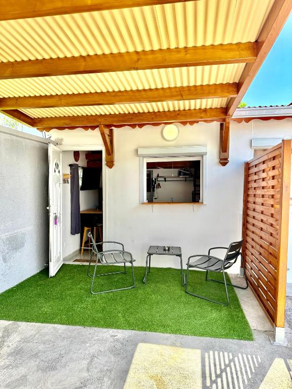 a patio with awning and chairs and grass at Studio cosy équipé à 5min de la plage in Vieux-Habitants