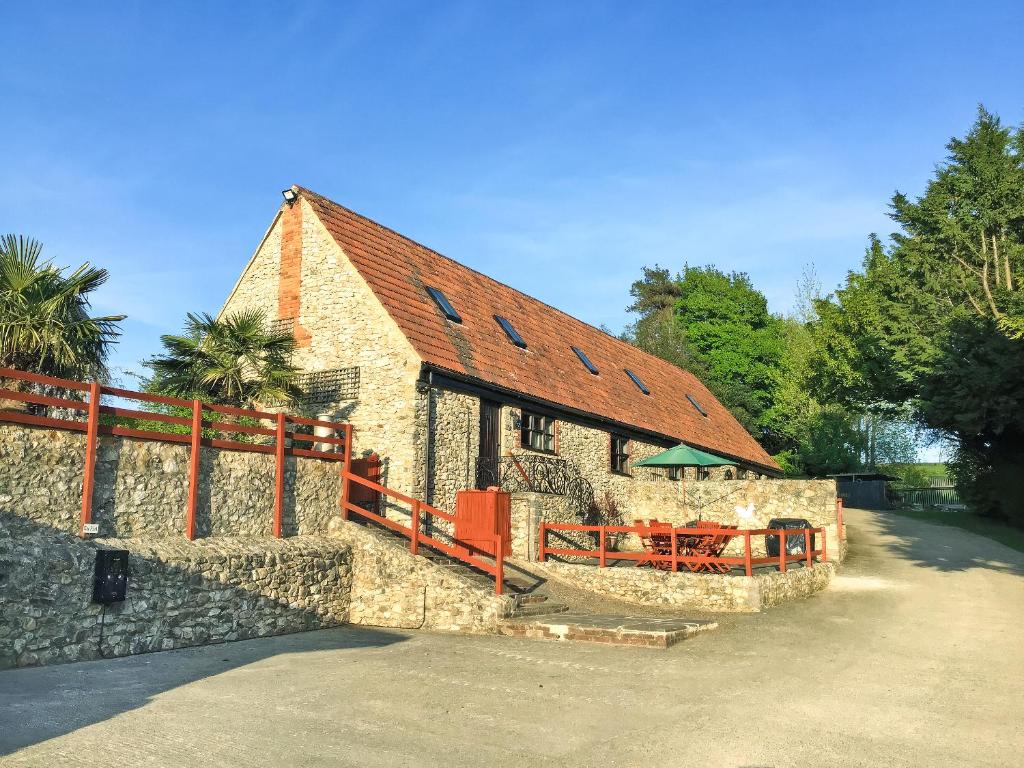 a large stone building with a red fence around it at Cider Cottage in Hawkchurch