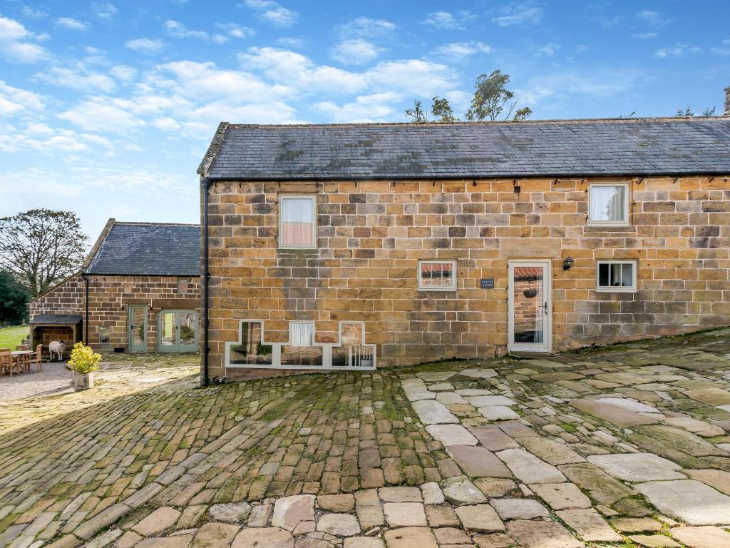 キャッスルトンにあるColtus Landsの庭に椅子が2脚置かれた古いレンガ造りの納屋